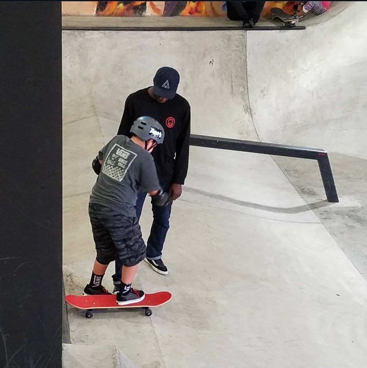 Leon Toppin teaching a young skateboarder in New York City