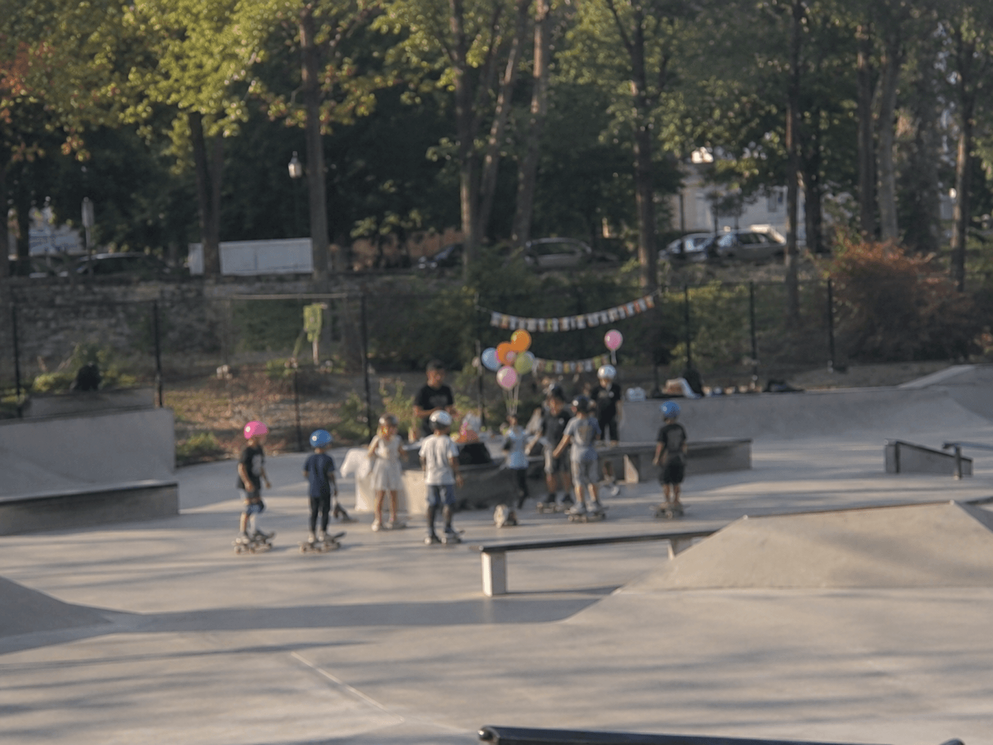 Kids at a skateboard birthday party with balloons and helmets at a skatepark